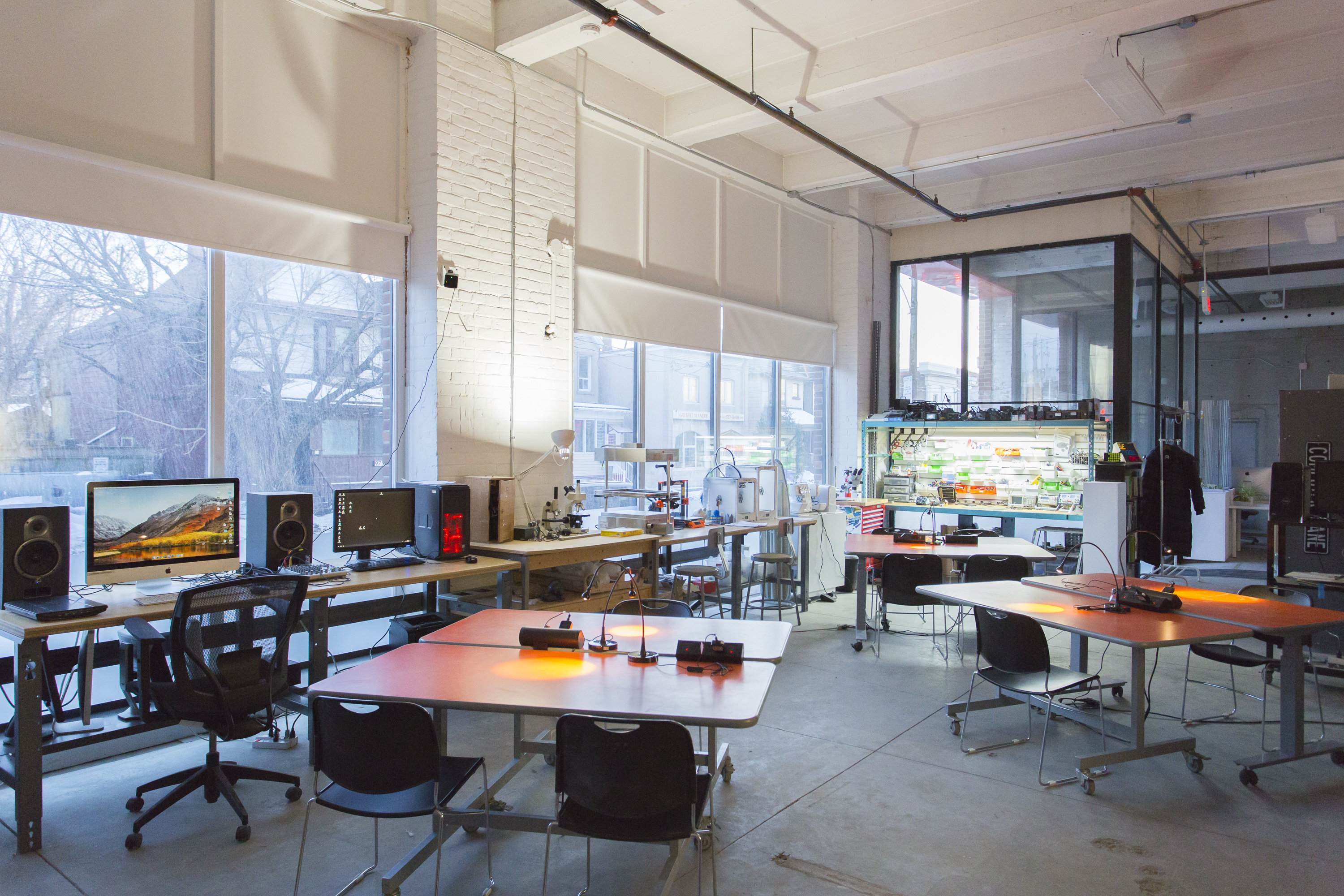 The InterAccess studio, including orange work tables, computer stations, an electronics bench and large open windows.